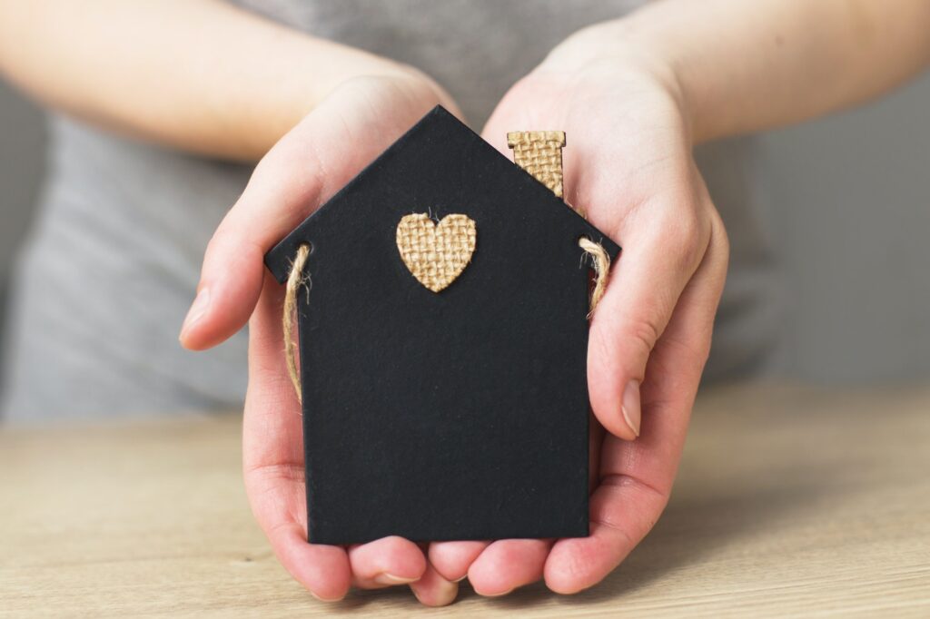 womans hand holding little toy house. Home insurance concept